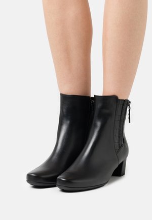 Černé kožené kotníkové boty s hladkým povrchem, čtvercovou špičkou, blokovým podpatkem a bočními elastickými panely s krokodýlím vzorem.