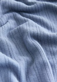 Blauwe gebreide stof met gestructureerde strepen en kleine gestippelde patronen, zachte textuur, licht gekreukte uitstraling en een gladde afwerking.