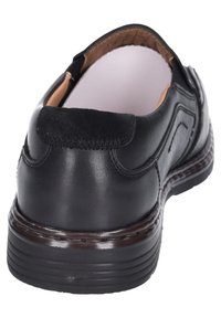 Scarpa in pelle nera con finitura liscia, tacco leggermente rialzato e dettagli di cucitura discreti. L'interno è foderato con un materiale di tonalità neutra.