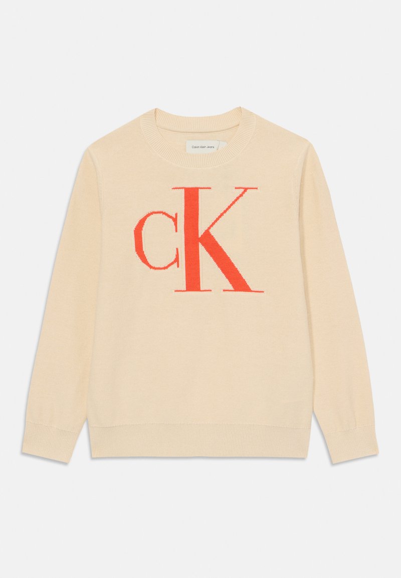 Svijetlosmeđi pulover od mekanog materijala, s velikim crvenim "CK" logotipom na sredini, okruglim izrezom i rebrastim manžetama.