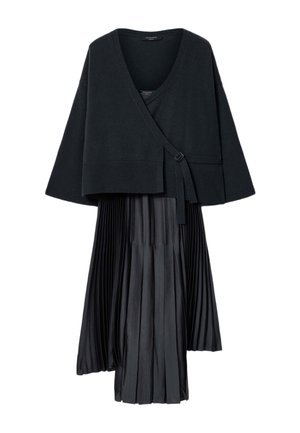 Sort cardigan med slå-om-stil og bindelukning, kombineret med et sort plisseret midiskørt, vist på hvid baggrund.