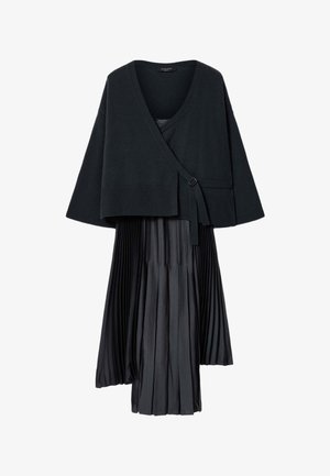 Sort cardigan med slå-om-stil og bindelukning, kombineret med et sort plisseret midiskørt, vist på hvid baggrund.