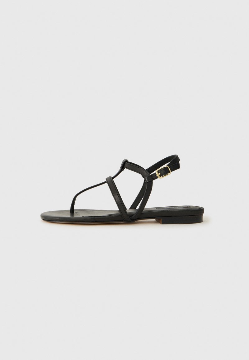 Sandalo nero in pelle con un design minimalista, caratterizzato da sottili cinturini, suola piatta e una piccola fibbia per la regolazione.