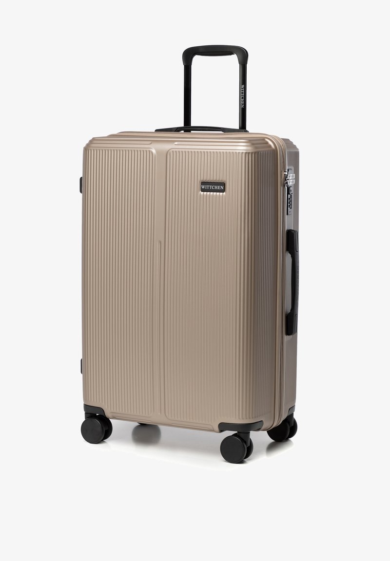 Valise rigide en beige métallique avec un design à rainures verticales, deux roues noires, une poignée rétractable et des accessoires de marque.