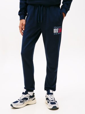 Mornarsko modri trenirčki iz mehke tkanine, z vrvico za prilagajanje v pasu, stranskimi žepi in pisanem logotipu "tommy jeans" na levem boku.