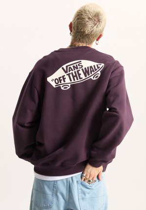 Fioletowa bluza z dużym białym logo "Vans 'Off the Wall'" z tyłu. Luźny krój z ściągaczami przy rękawach i miękką teksturą.
