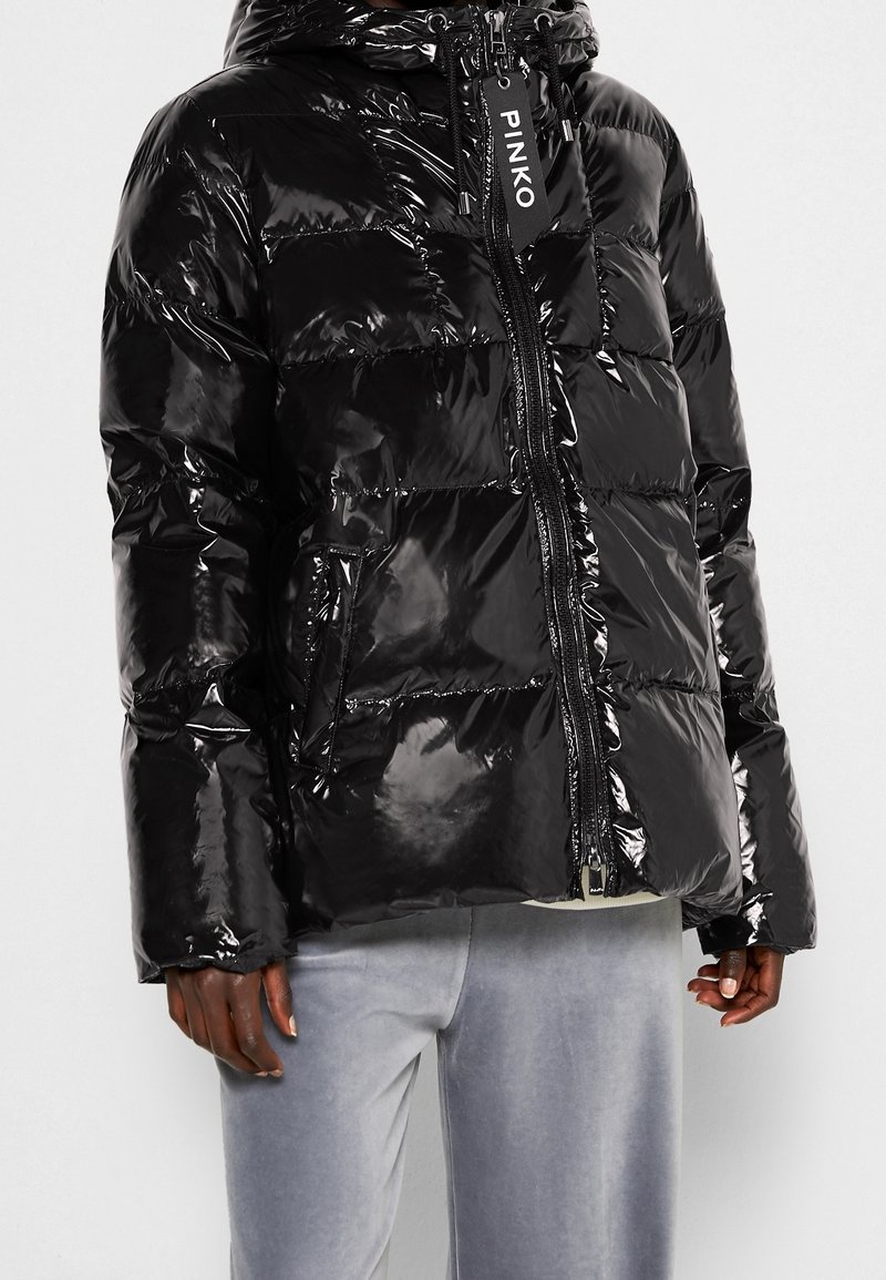 Černá péřová bunda s lesklým povrchem, vybavená kapucí, zipovým zapínáním a horizontálním prošíváním. Obsahuje přední kapsy a štítek s logem.
