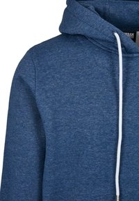 Felpa blu realizzata in tessuto morbido, con una finitura testurizzata, cordino bianco regolabile e un classico design con tasca a marsupio.