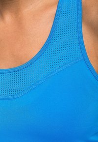 Niebieski sportowy top bez rękawów z oddychającą siateczką z małymi perforacjami, gładką teksturą materiału i okrągłym dekoltem.