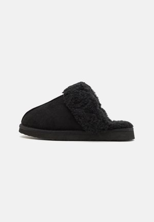 Czarna wsuwana kapcie z grubą, puszystą podszewką i podeszwą z polaru, pokazane z boku na białym tle.