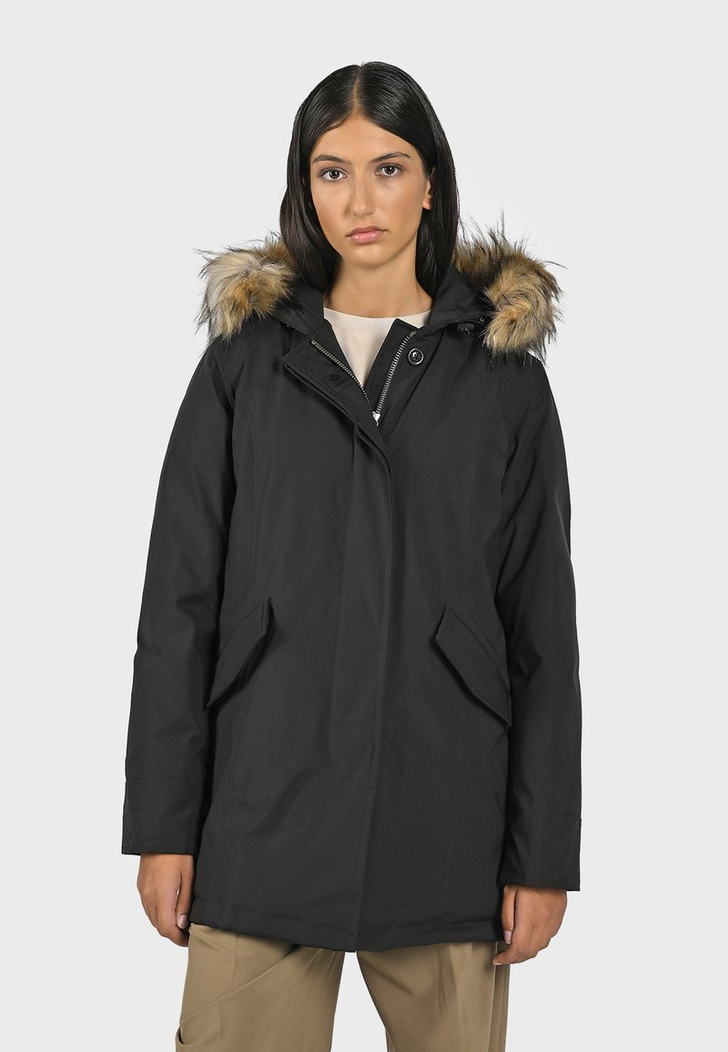 Svart parkas med huva i päls, dragkedja och tryckknapps stängning, två framfickor och ett slankt, vattentätt yttermaterial.