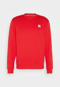Sudadera roja hecha de tela suave, con mangas largas, cuello redondo y un pequeño parche con logo blanco en el pecho izquierdo.