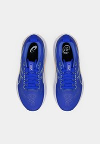 Zapatillas deportivas azules con un upper texturizado, cordones y un diseño ligero. Acentos destacados en un tono más claro y una marca prominente.