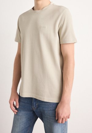 Hellbeiges T-Shirt mit kurzen Ärmeln aus weicher Baumwolle und Rundhalsausschnitt. Mit einem dezenten, geprägten "BOSS"-Logo auf der Brust.