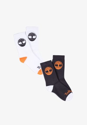 Twee paar enkelsokken, één wit met oranje tenen en zwart boomlogo, één zwart met witte tenen en oranje boomlogo, plat naast elkaar gelegd.