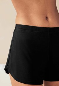 Zwarte katoenen shorts met een elastische tailleband, met een gladde textuur en zijslitsen voor gemakkelijke beweging.