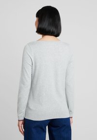 Pull gris à manches longues avec un col rond. Doté d'un ourlet et de manches côtelés avec des rayures contrastantes aux poignets. Texturé lisse.