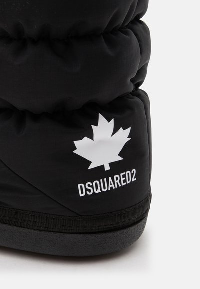Gros plan sur un talon de basket noire matelassée avec un logo feuille d’érable blanc et le texte DSQUARED2 au-dessus de la semelle noire.