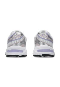 Białe i srebrne buty sportowe z siateczkową cholewką, fioletowymi akcentami, amortyzowanym obcasem oraz teksturowaną czarną podeszwą. Okrągły kształt z odblaskowymi detalami.