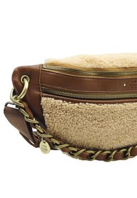 Sac à main en cuir marron avec une partie supérieure crémeuse, texturée et duveteuse. Présente une bandoulière en chaîne dorée et une poche zippée à l'avant.