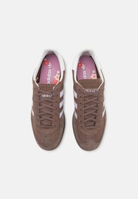 Bruna kordtoyskors med vita ränder, med en texturerad ovandel, runda skosnören och en rosa innersula med blommönster.