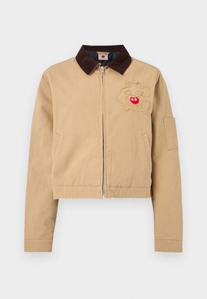 Beežist lukuga jope tumepruuni kraega ja narmendava kontuuriga kujundusega, millel vasakul rinnal on punane südamekuju, pikad varrukad ja ees taskud.