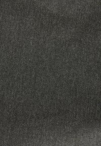 Fekete farmeranyag sima textúrával, finom twill szövésű, enyhe színeltérésekkel, amelyek finom mélységérzetet keltenek.
