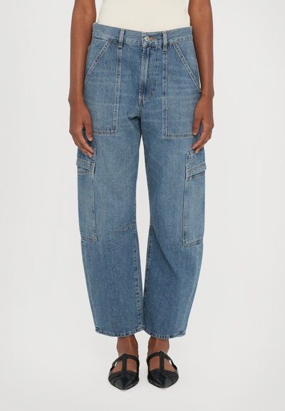 Pantaloni cargo din denim albastru, cu talie înaltă, picioare late, detalii cu multiple buzunare și un finisaj ușor decolorat. Completați cu încălțăminte neagră.