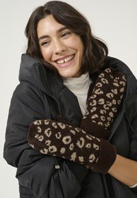 Smešane smeđe pletene rukavice s uzorkom leopard, s rebrastim rubovima, koje nosi osoba u crnoj puffer jakni i svijetlom turtlenecku.