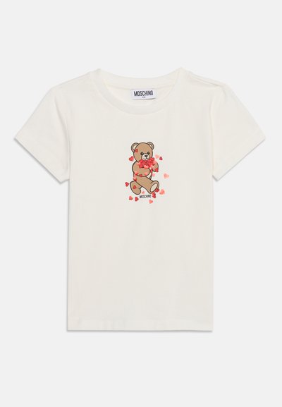 T-shirt blanc manches courtes pour enfants avec un motif d'ourson entouré de cœurs rouges et le nom de la marque Moschino en dessous.