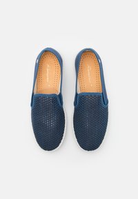 Marineblauwe mesh instappers met geperforeerde bovenkant, contrasterende witte zool en gepolsterde binnenzool voor comfort. Ronde neusdesign.