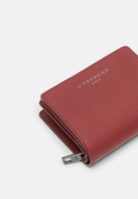 Red leather wallet with textured surface, featuring a silver logo "LIEBESKIND BERLIN" and a metal zipper pull detail.