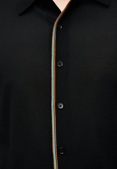 Μαύρο πουκάμισο με κουμπιά από υφασμάτινη ύφη, με πολύχρωμη ριγέ λεπτομέρεια κατά μήκος της λωρίδας κουμπιών και μαύρα κουμπιά.