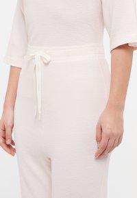 Σετ ρούχων σε παλ ροζ απόχρωση με υφή και ριγωτό μοτίβο. Διαθέτει κορδόνι στη μέση και κοντά μανίκια, προσφέροντας μια άνετη εφαρμογή.