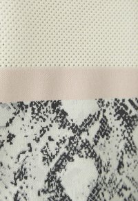 Textil mit einem strukturierten weißen Netzoberteil, einem hellrosa Streifen und einem schwarz-weißen abstrakten Muster darunter, das Kontrast und Details zeigt.