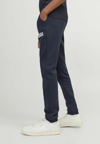 Navyblauwe sweatpants met een comfortabele pasvorm, voorzien van een wit logo op de linker bovenbeen, zijzakken en geribbelde boorden. Casual ontwerp.