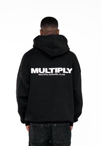 Felpa nera con cappuccio che presenta un grande logo bianco stampato "MULTIPLY" sulla schiena. Tessuto morbido con un cappuccio ampio e vestibilità rilassata.