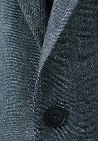 Close-up of a blue textured fabric jacket with a lapel and a single dark button fastened.