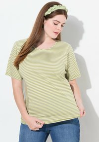 Camiseta de rayas verde claro con mangas cortas y cuello redondo, combinada con jeans azules. La tela parece suave y tiene un ajuste relajado.