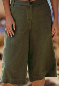 Oliven grønne culottes lavet af hør, med et bredt ben design, frontknaplukning og synlig syning langs sømene.