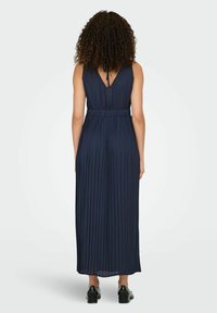 Navy pleated maxi dress with a V-back and adjustable neck tie. Features a fitted waist, flowing fabric, and a smooth texture.