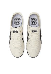 White leather sneakers with black stripes, round toe, and lace-up front. Features a padded collar and contrasting logo on the tongue.