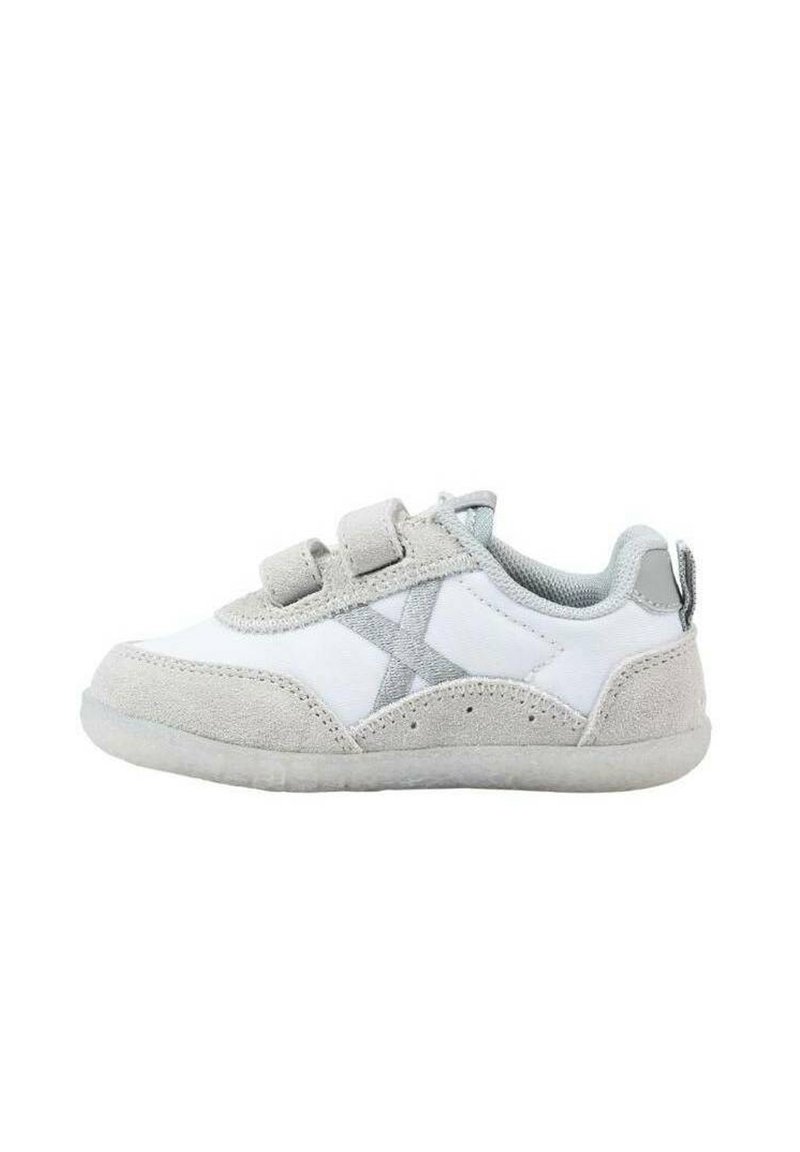 Zapatilla blanca con acentos de ante gris, correas de gancho y bucle, y puntera redondeada. Presenta una suela texturizada y un diseño prominente en forma de "X".