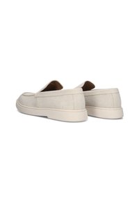 Beige instappers met een bovenwerk van gestructureerde stof en een lichte rubberen zool, met een laag profiel en minimalistische designelementen.