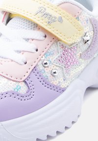 Παιδικό αθλητικό παπούτσι με παστέλ μοβ, ροζ και κίτρινα στοιχεία, διακοσμημένο με παγιέτες σε σχήμα αστεριών, ασημένιες λεπτομέρειες και κίτρινο λουράκι με κεντημένο κείμενο.