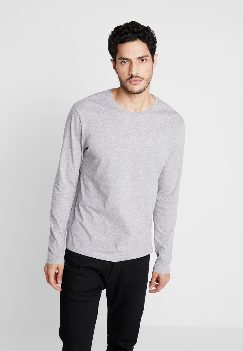 Gray long-sleeve t-shirt in cotton blend with a round neckline, paired with black pants; smooth texture and fitted style.