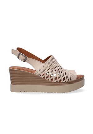 Beige wedge sandals featuring a cut-out pattern, adjustable ankle strap, and textured platform sole. Smooth leather upper.