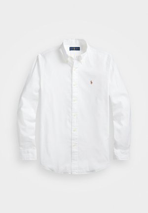 Camicia bianca in cotone con bottoni, a maniche lunghe, caratterizzata da un piccolo logo ricamato sul petto e bottoni gialli. Texture liscia.