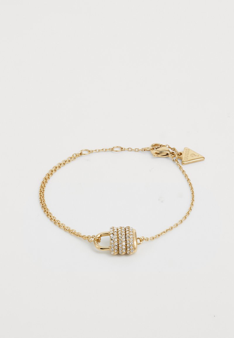 Bracciale in catena d'oro con charm a forma di lucchetto, adornato con cristalli trasparenti. Texture liscia con una finitura lucida, include una chiusura e un'etichetta con logo.
