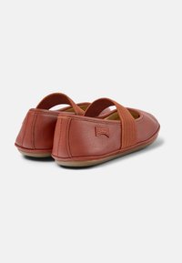 Rote Lederflats mit elastischen Riemen, runder Zehenform, strukturiertem Finish und Gummisohlen. Camper-Logo auf der Hinterseite eingestanzt.